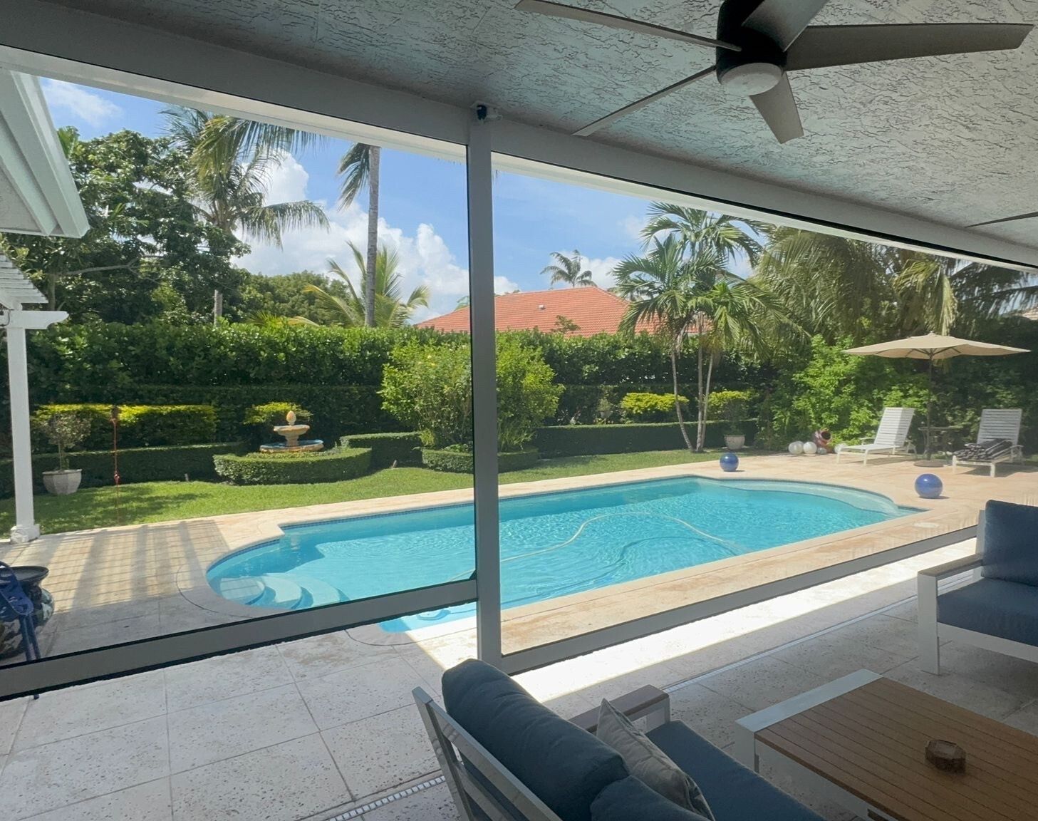 Screened lanai looking out over a pool and palms