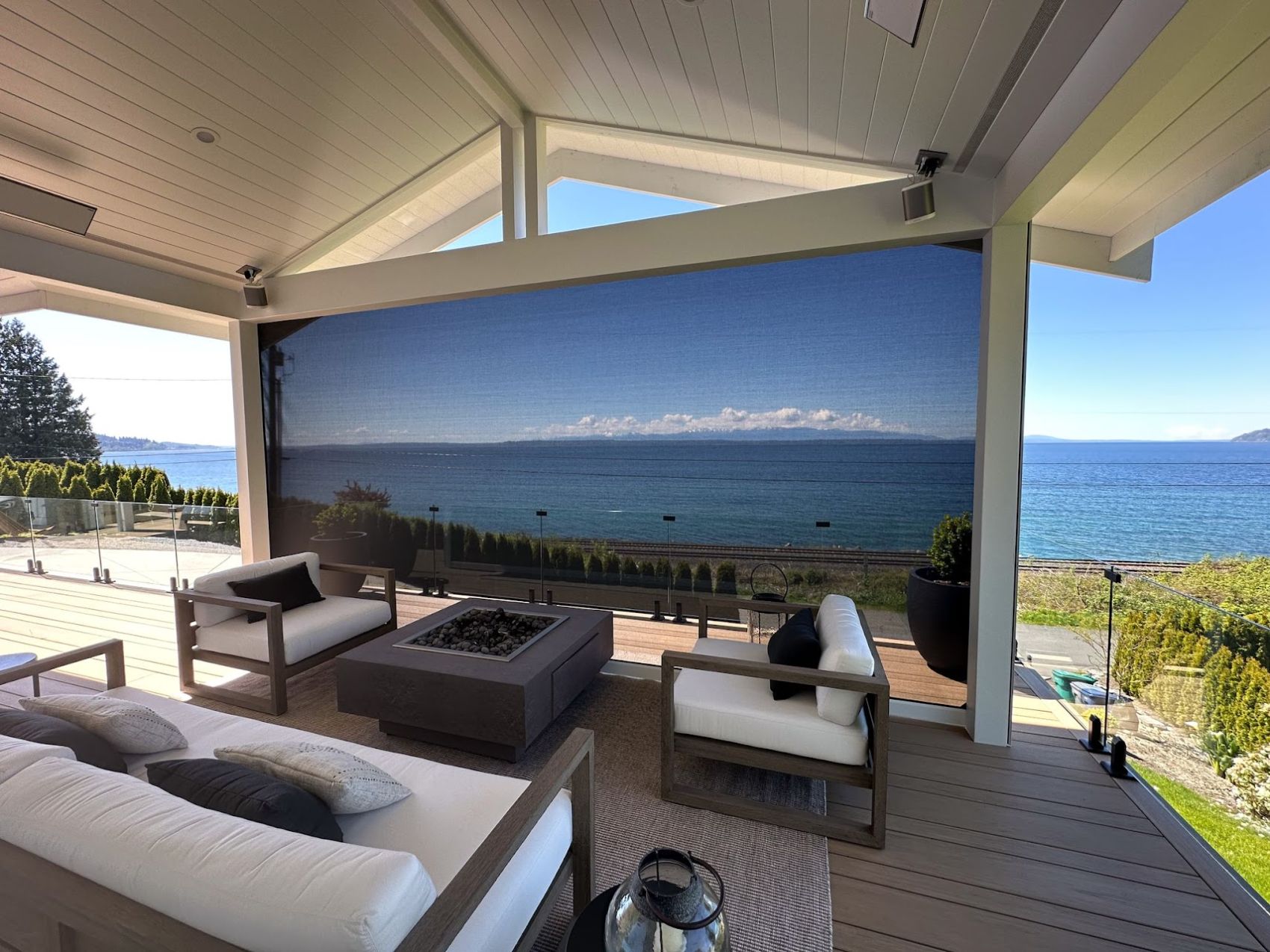 Covered lounge with a lowered screen framing a view of the Sound