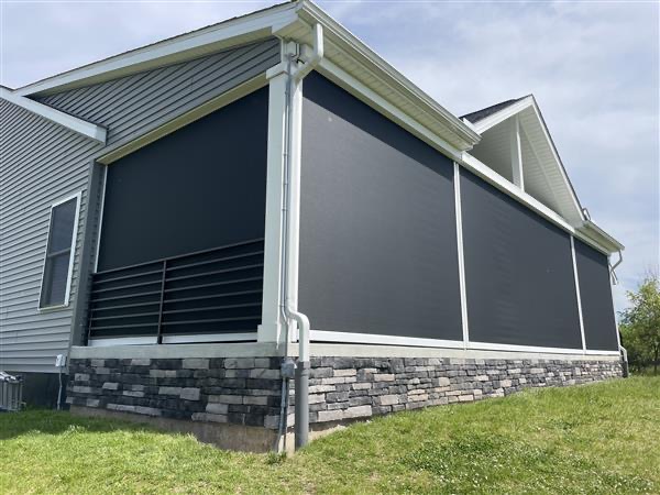 Dark screens enclosing a raised porch above a stone base