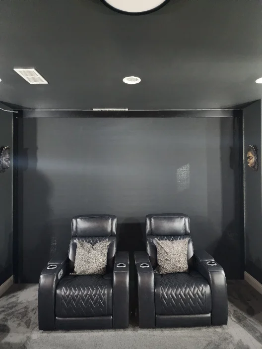 Home theater with a dark screen lowered behind two leather recliners
