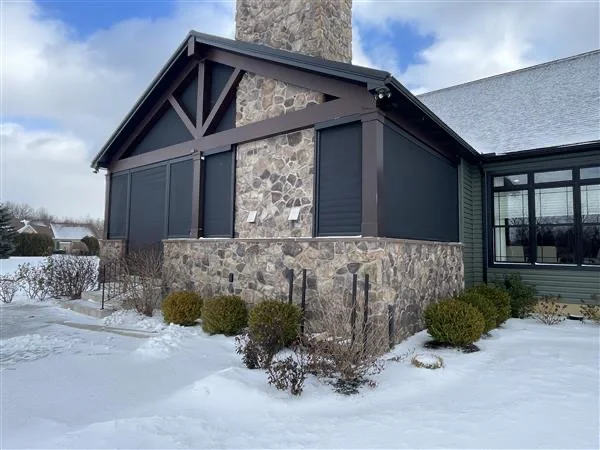 Dark screens enclosing a stone-and-timber gable porch in winter