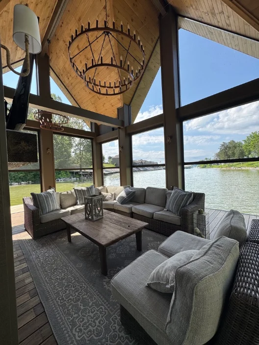 Screened lakeside porch under a timber-truss ceiling with a lake view