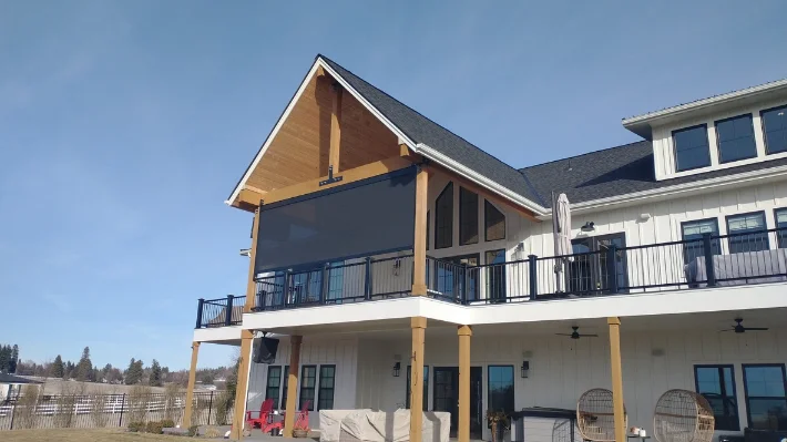 Two-story farmhouse with motorized screens lowered across a gable-end deck