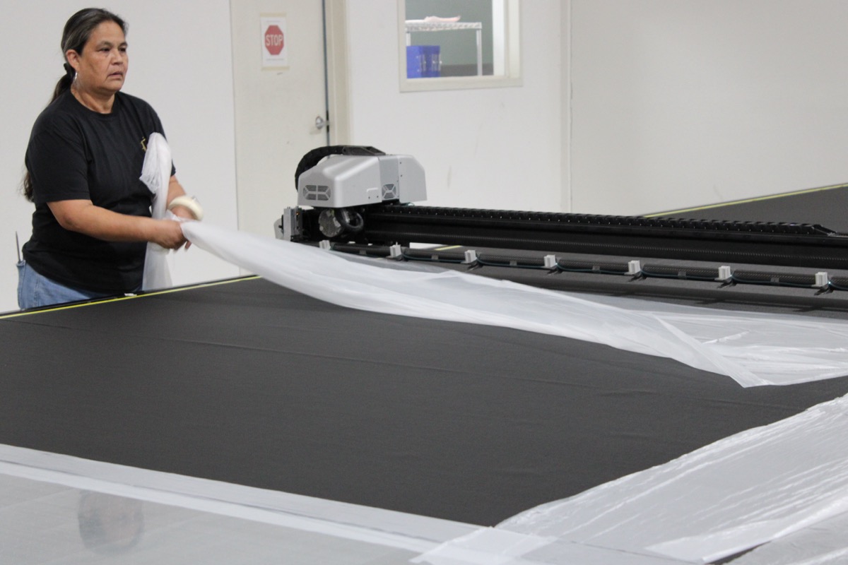 A Templar team member guiding screen fabric onto the CNC cutting table